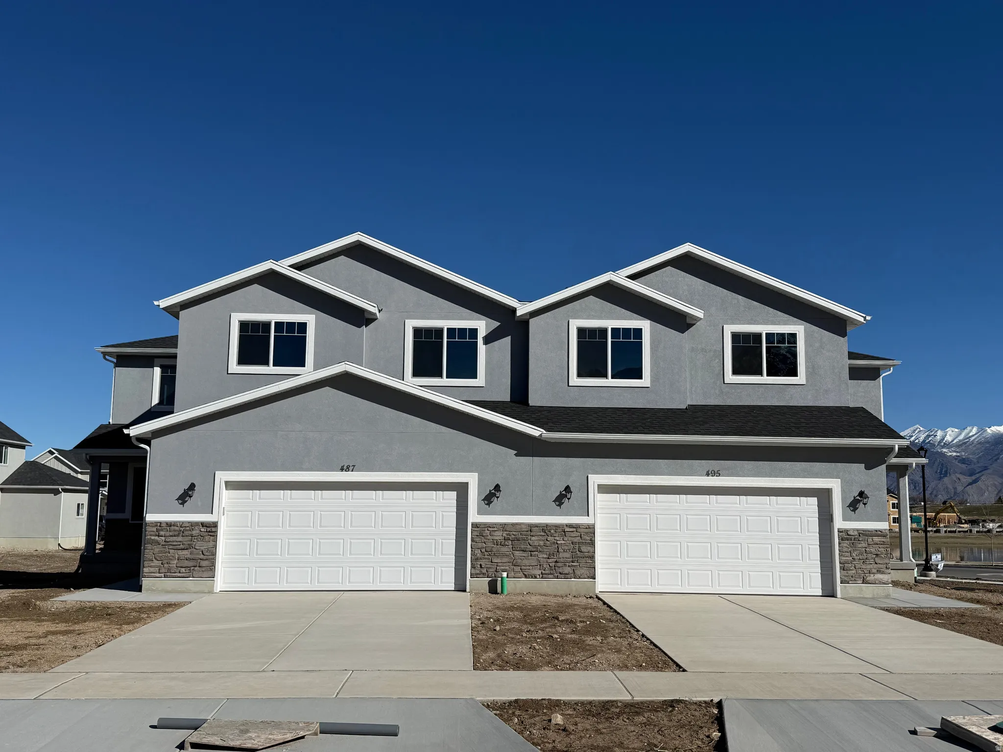 View of front of house featuring stone siding, stucco siding, concrete driveway, and an attached garage