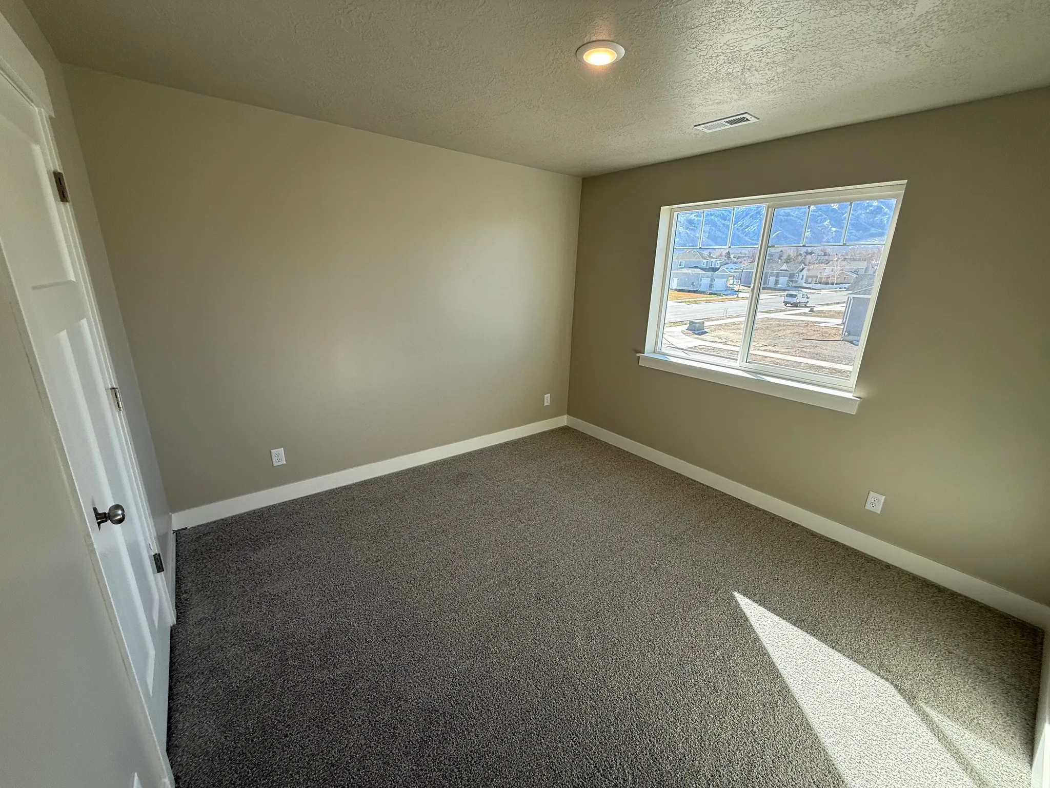 Empty room featuring dark colored carpet and a textured ceiling