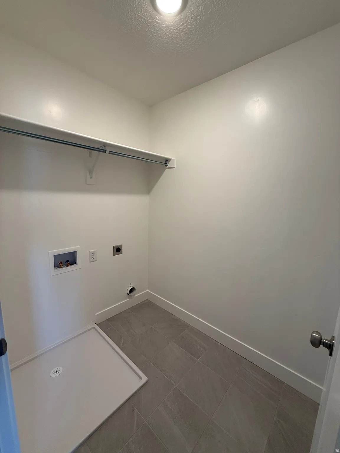 Laundry room featuring electric dryer hookup, a textured ceiling, hookup for a washing machine, and dark tile patterned flooring