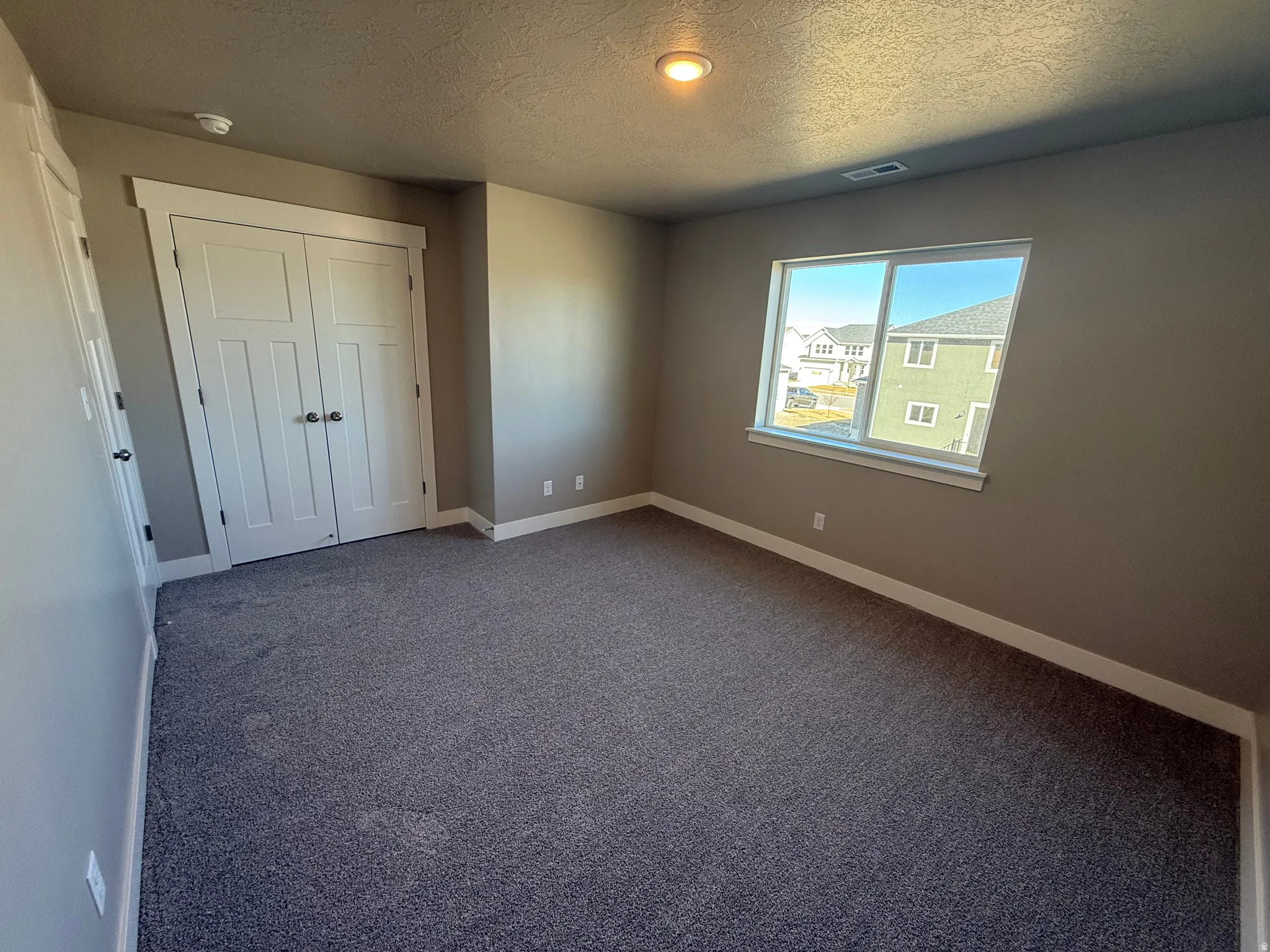Unfurnished bedroom featuring carpet floors, a closet, and a textured ceiling