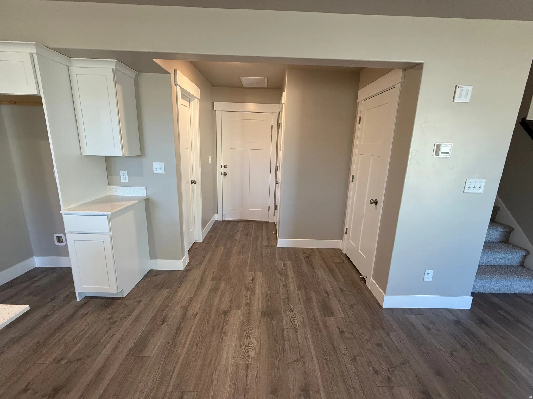 Hallway with stairway and dark wood-style flooring