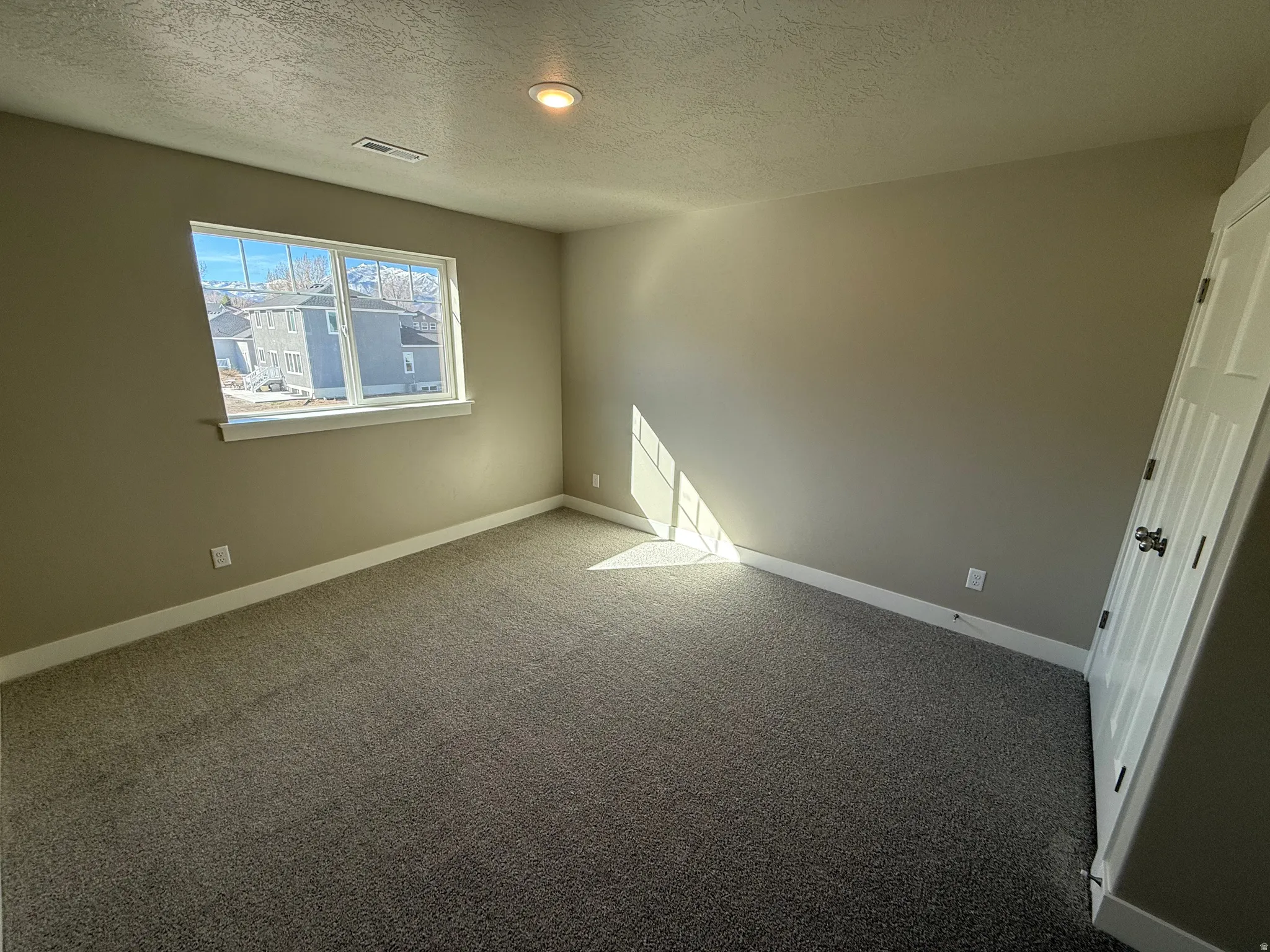 Carpeted spare room featuring baseboards and a textured ceiling