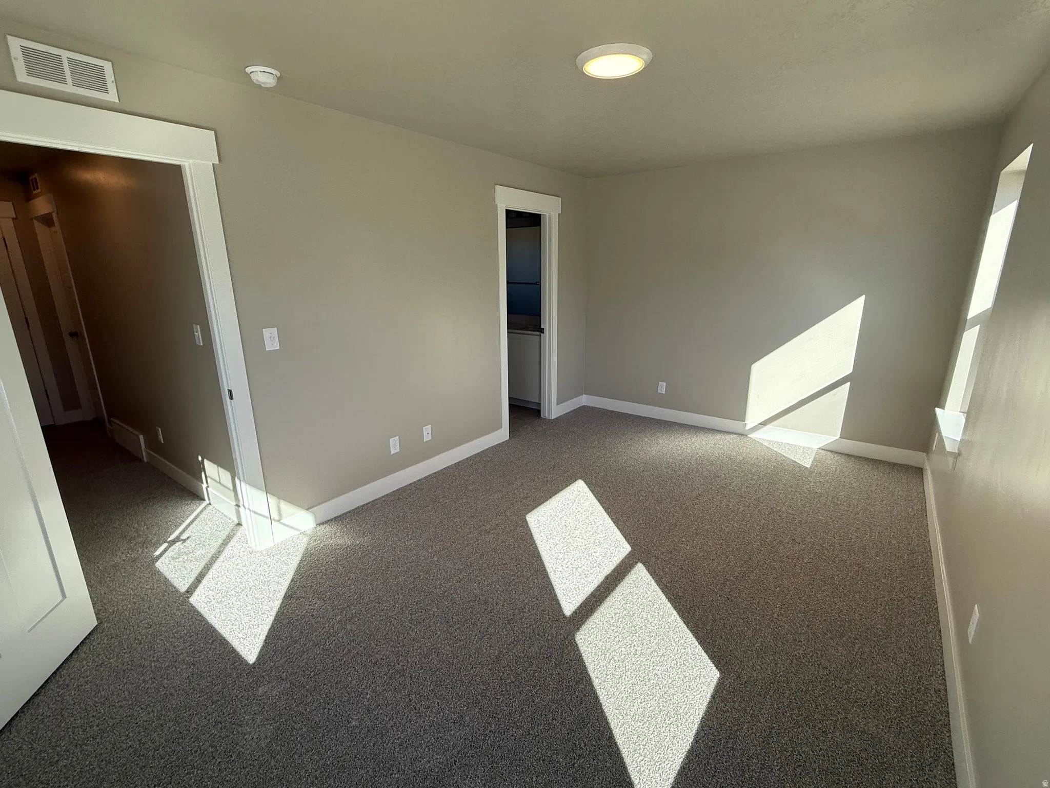 Unfurnished bedroom with light carpet and baseboards