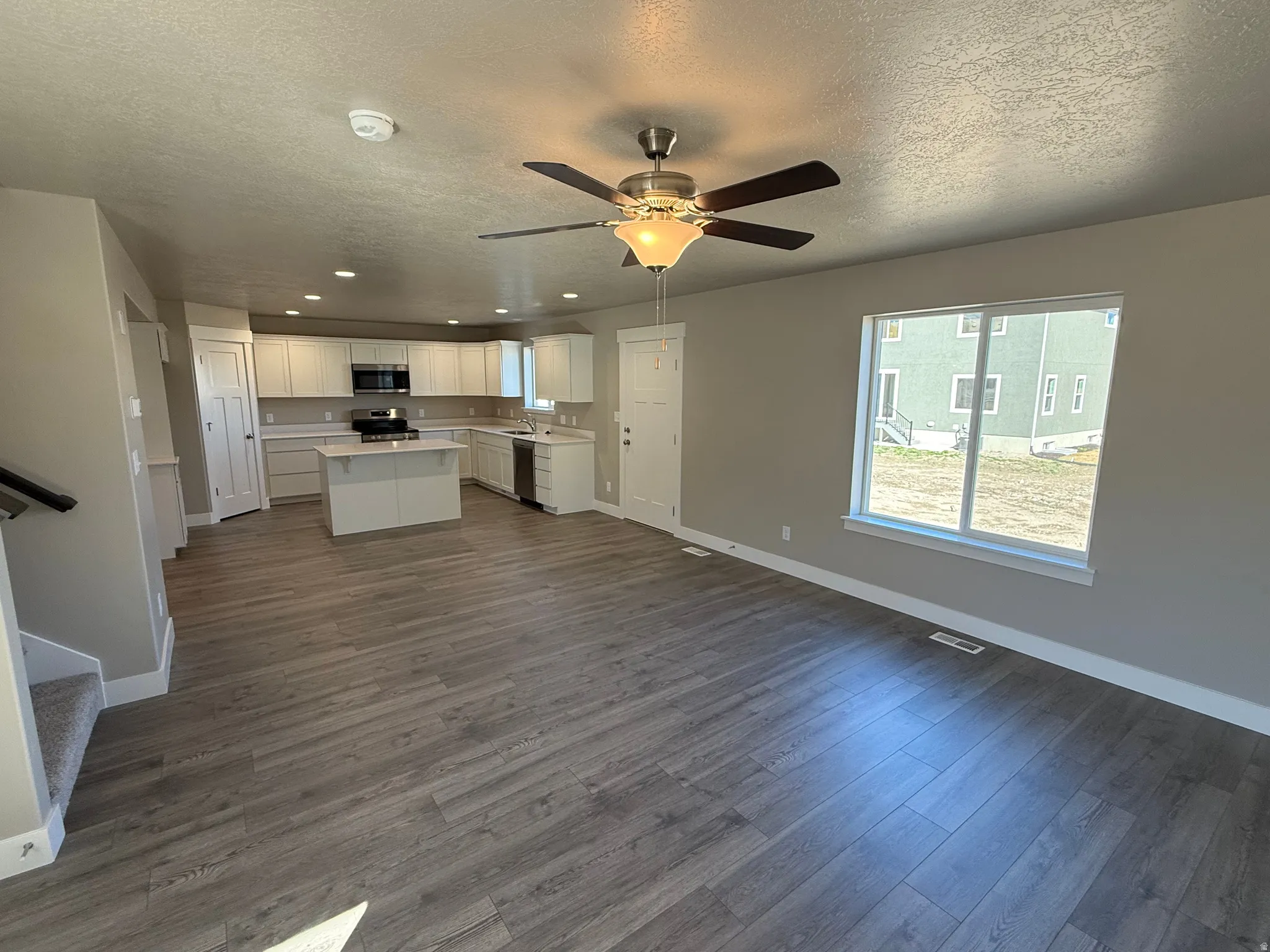 Kitchen with a kitchen island, open floor plan, light countertops, a textured ceiling, and white cabinets
