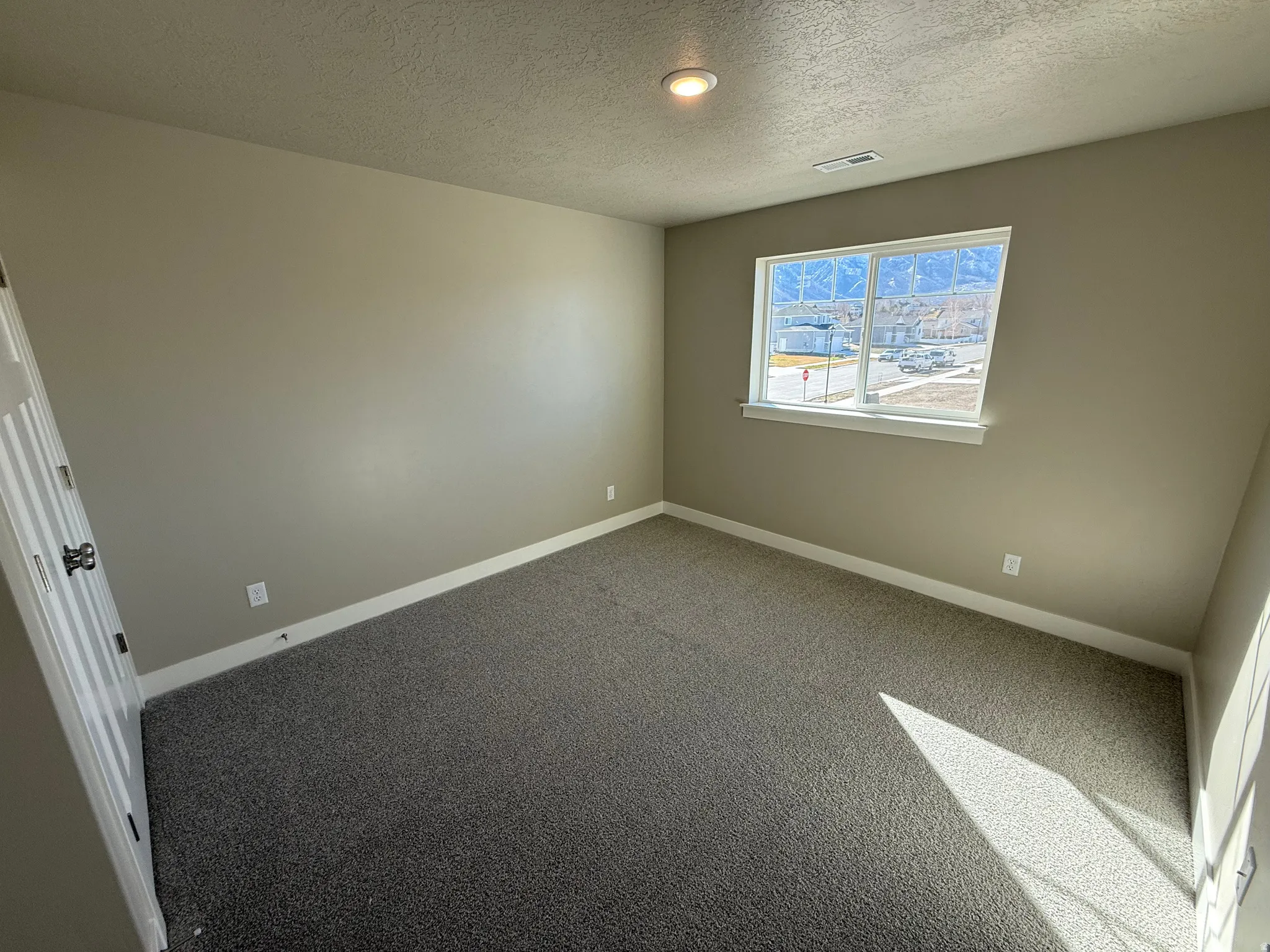 Carpeted spare room with baseboards and a textured ceiling