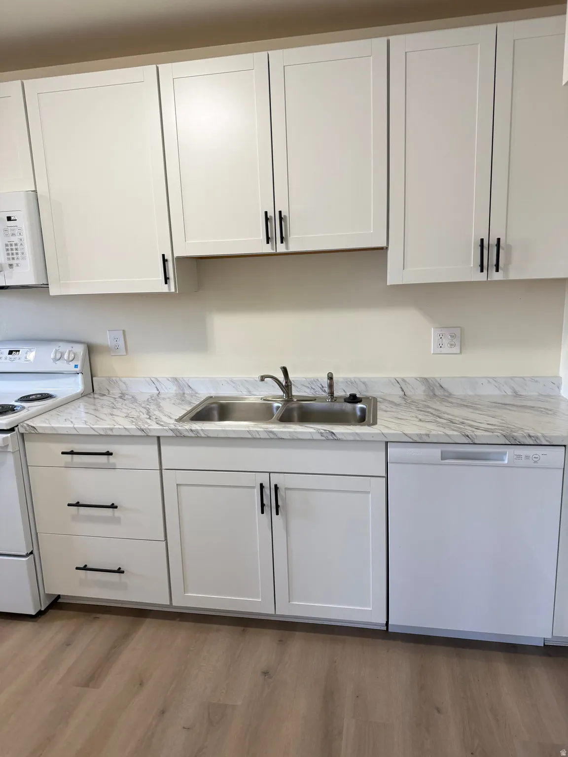 Kitchen with white appliances, light countertops, and white cabinets
