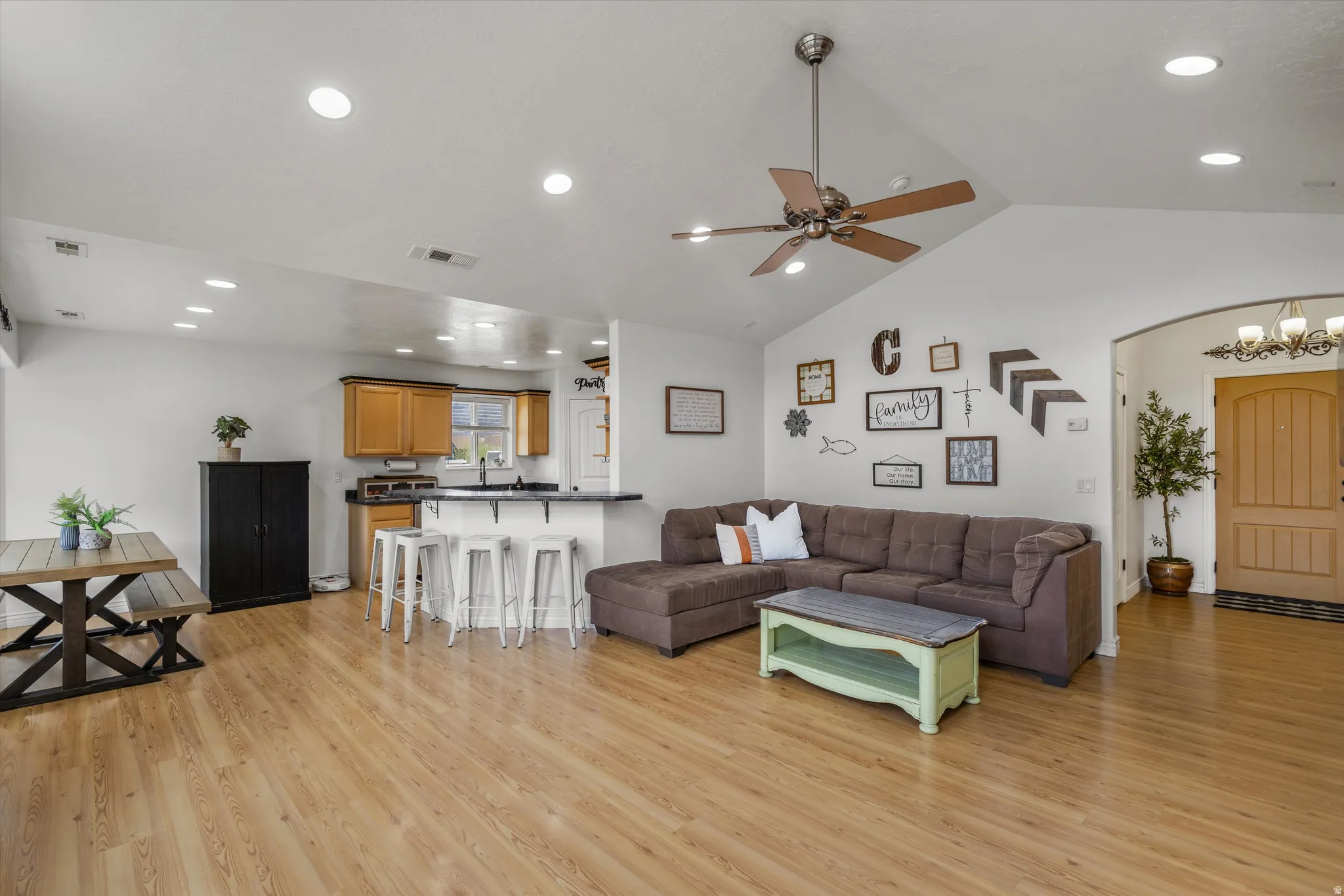 Living area with recessed lighting, light wood finished floors, arched walkways, vaulted ceiling, and ceiling fan