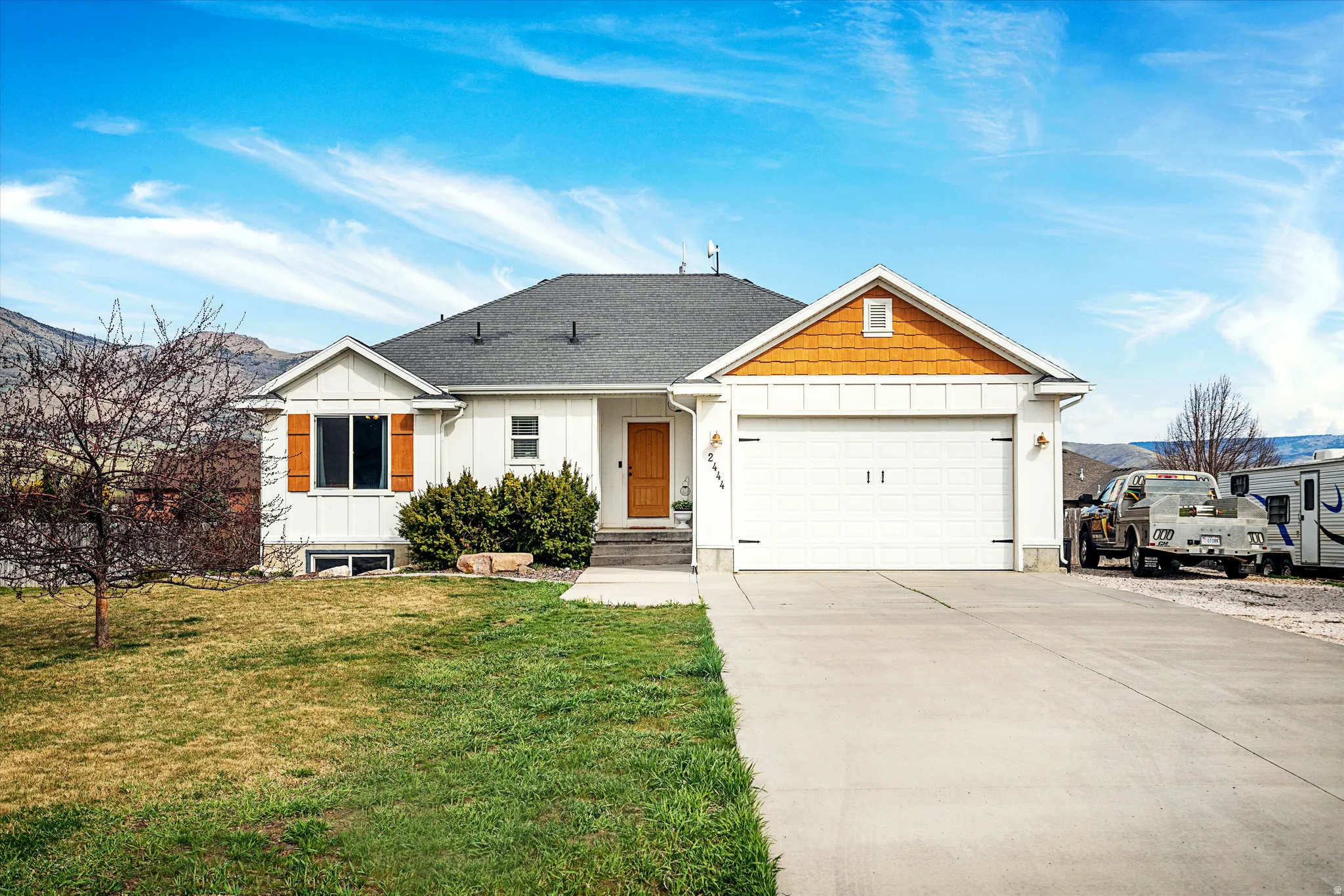 View of front of house with board and batten siding, driveway, a garage, and roof with shingles