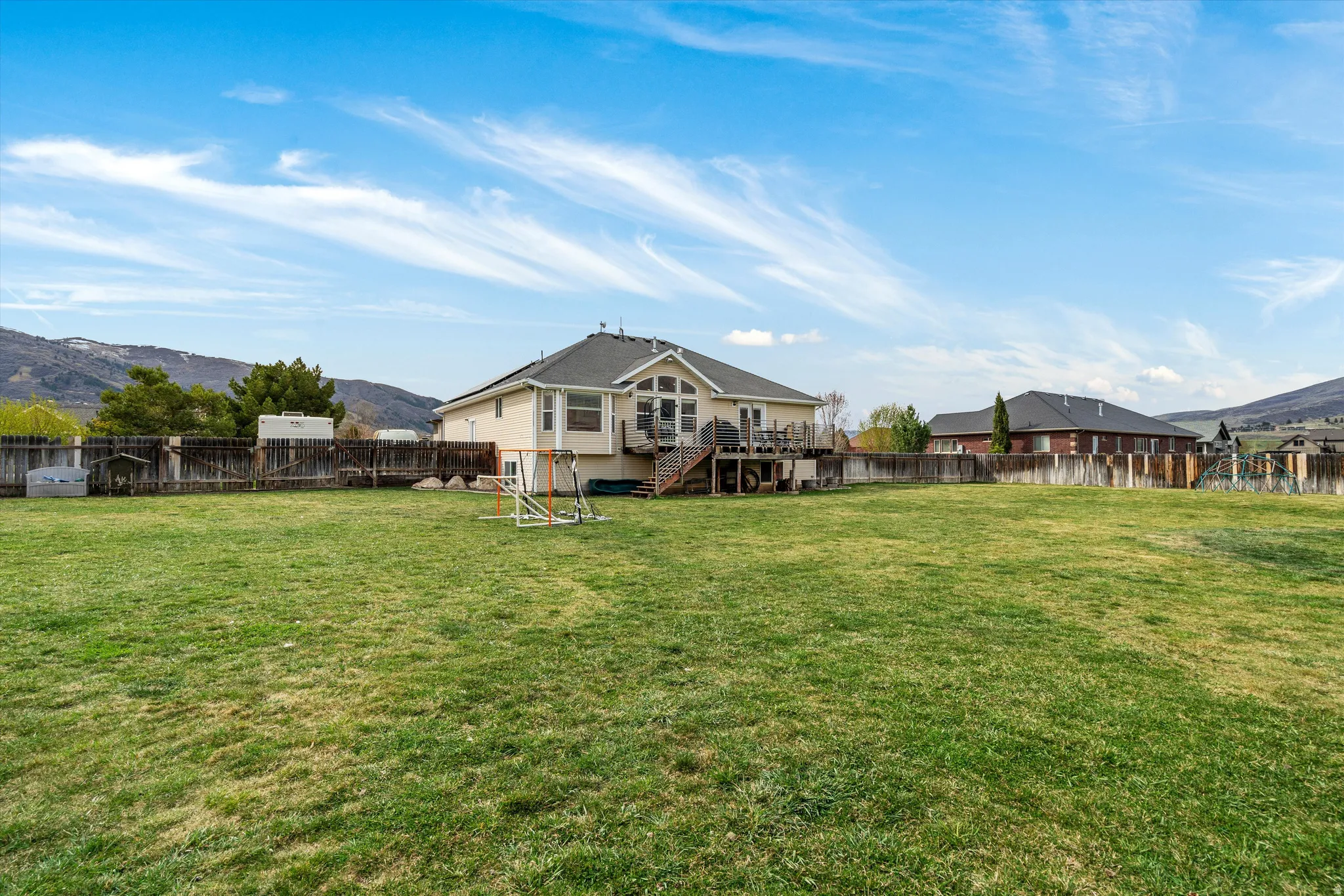 Rear view of house with a deck with mountain view and a fenced backyard