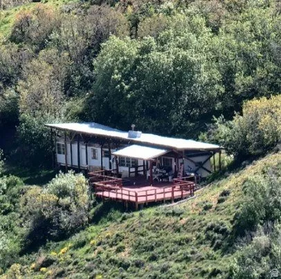 View of front of home with a deck and a forest view