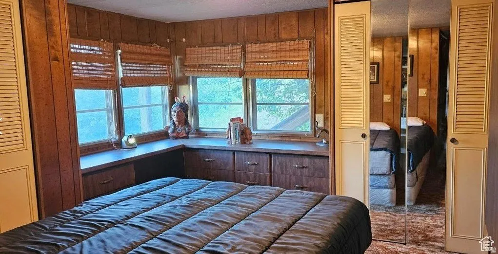 Bedroom featuring a closet and wood walls