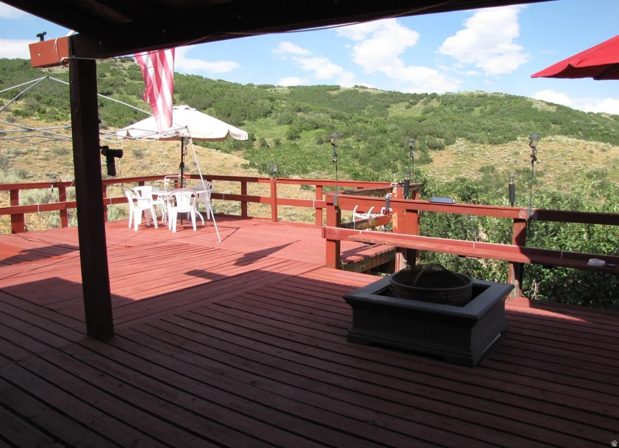 Wooden terrace featuring outdoor dining space and a view of trees