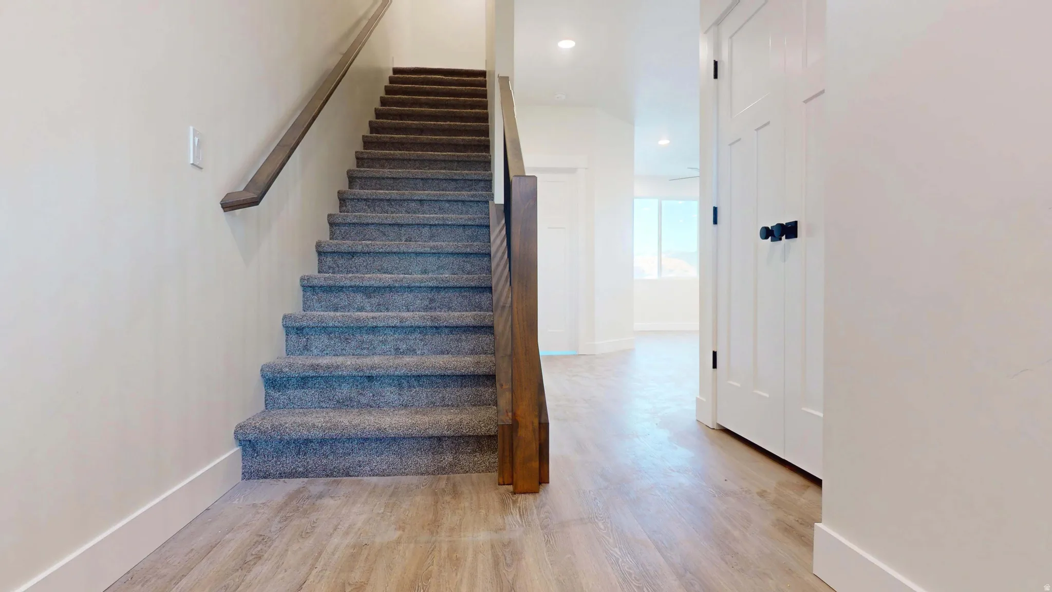 Stairway with wood finished floors and recessed lighting