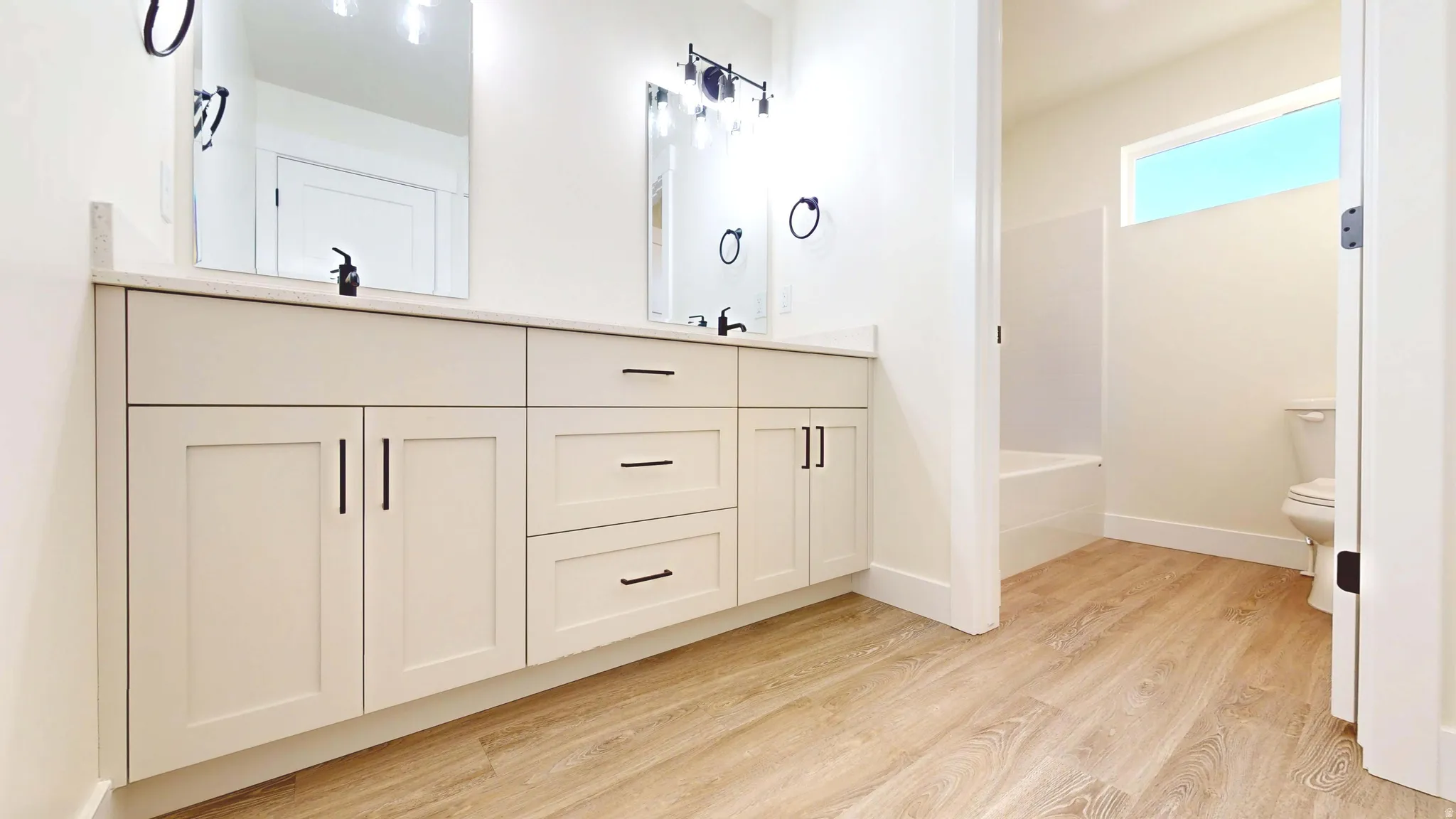 Bathroom with double vanity and light wood-type flooring