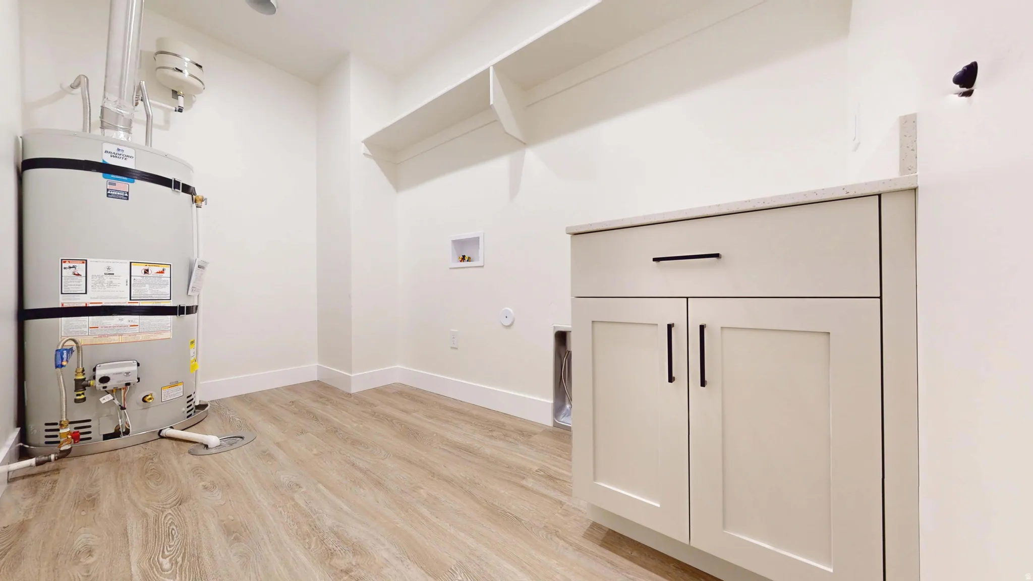 Laundry room with hookup for a gas dryer, light wood-style floors, water heater, and washer hookup