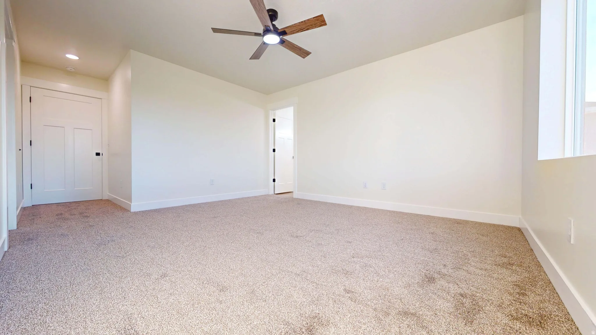 Unfurnished room with light colored carpet and ceiling fan