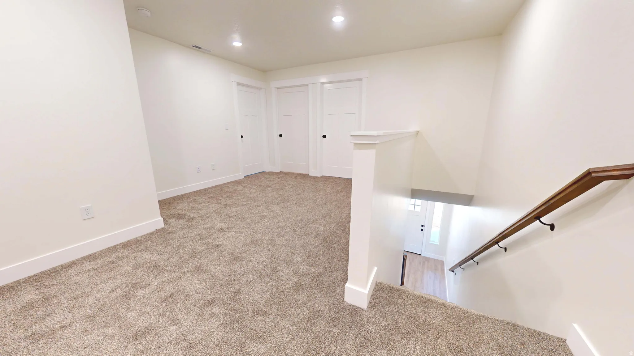 Staircase with carpet floors and recessed lighting