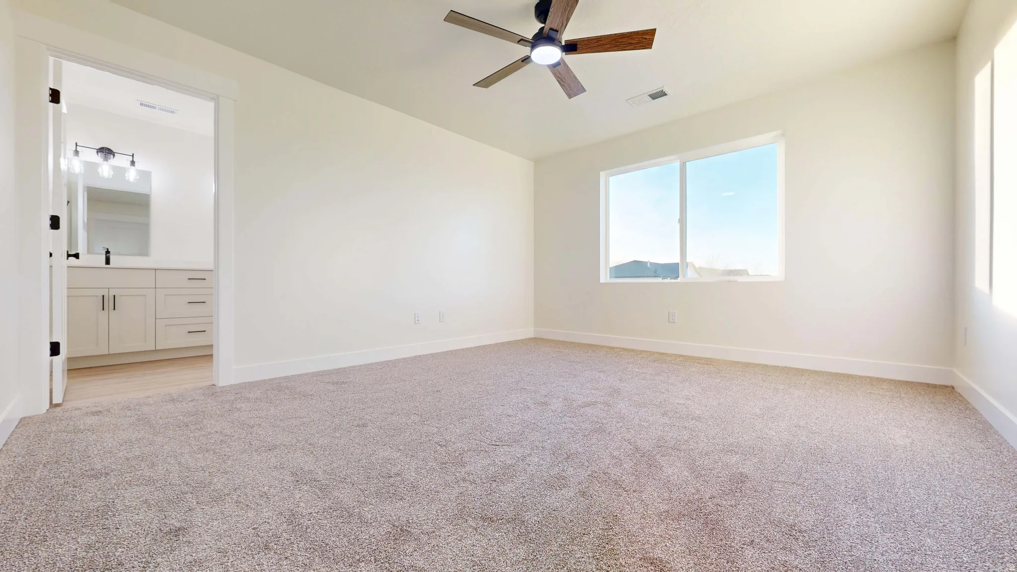 Unfurnished bedroom featuring light carpet, a ceiling fan, and ensuite bathroom