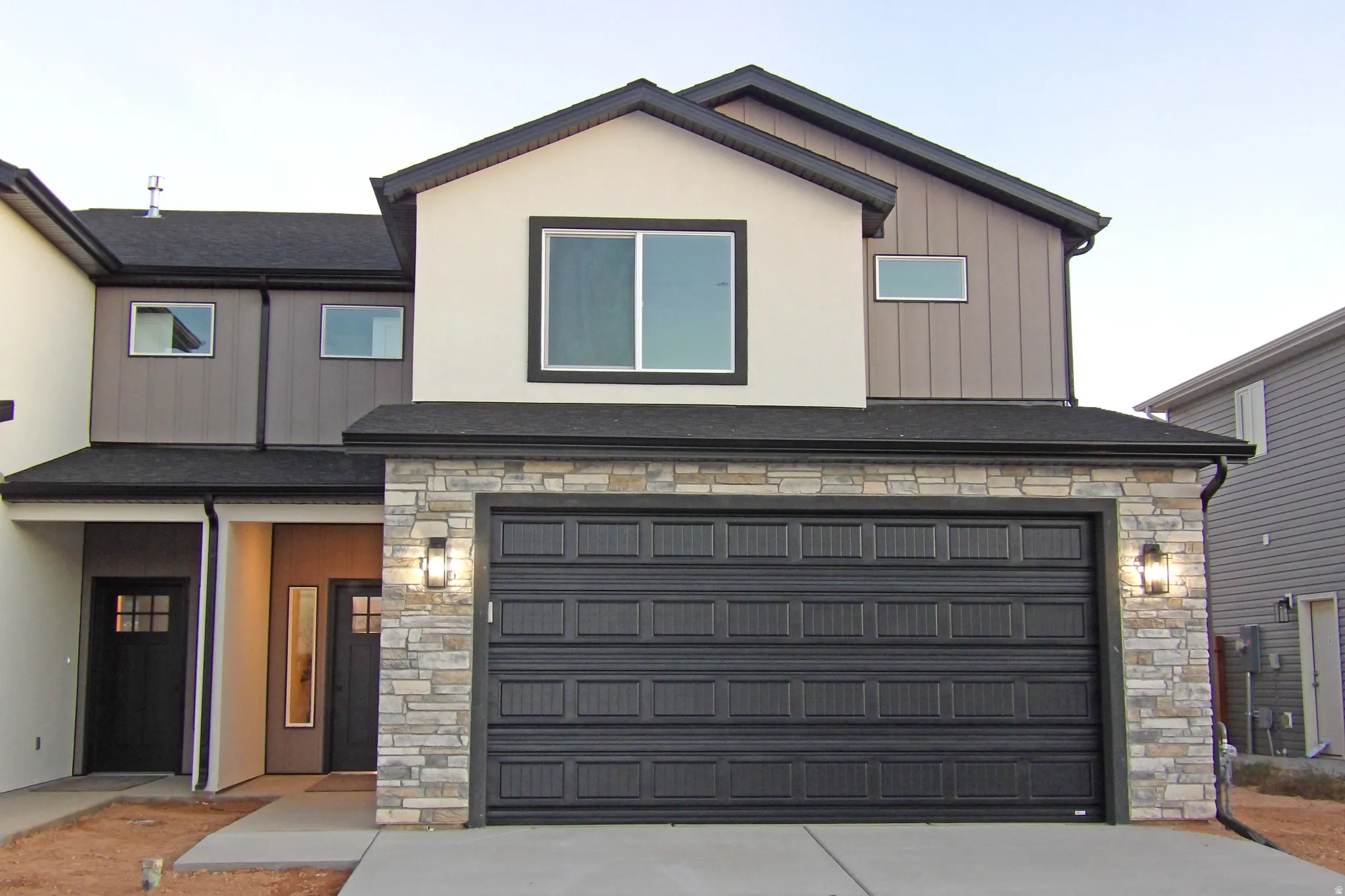 View of front of house with stone siding, board and batten siding, and driveway