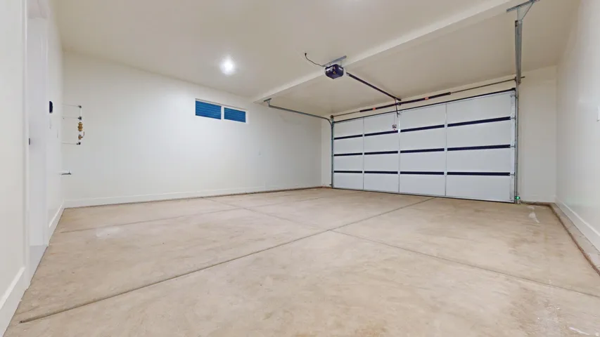 Garage featuring baseboards and a garage door opener
