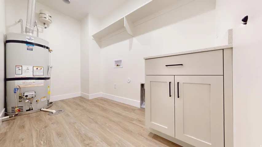 Laundry room with hookup for a gas dryer, light wood-style floors, water heater, and washer hookup