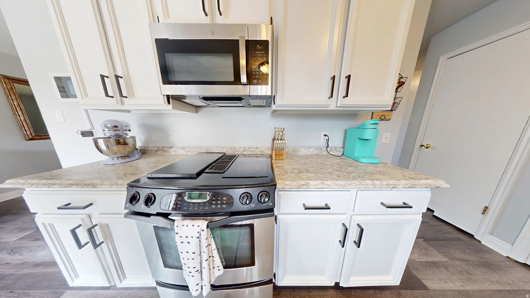 Kitchen featuring stainless steel appliances, light countertops, and white cabinetry