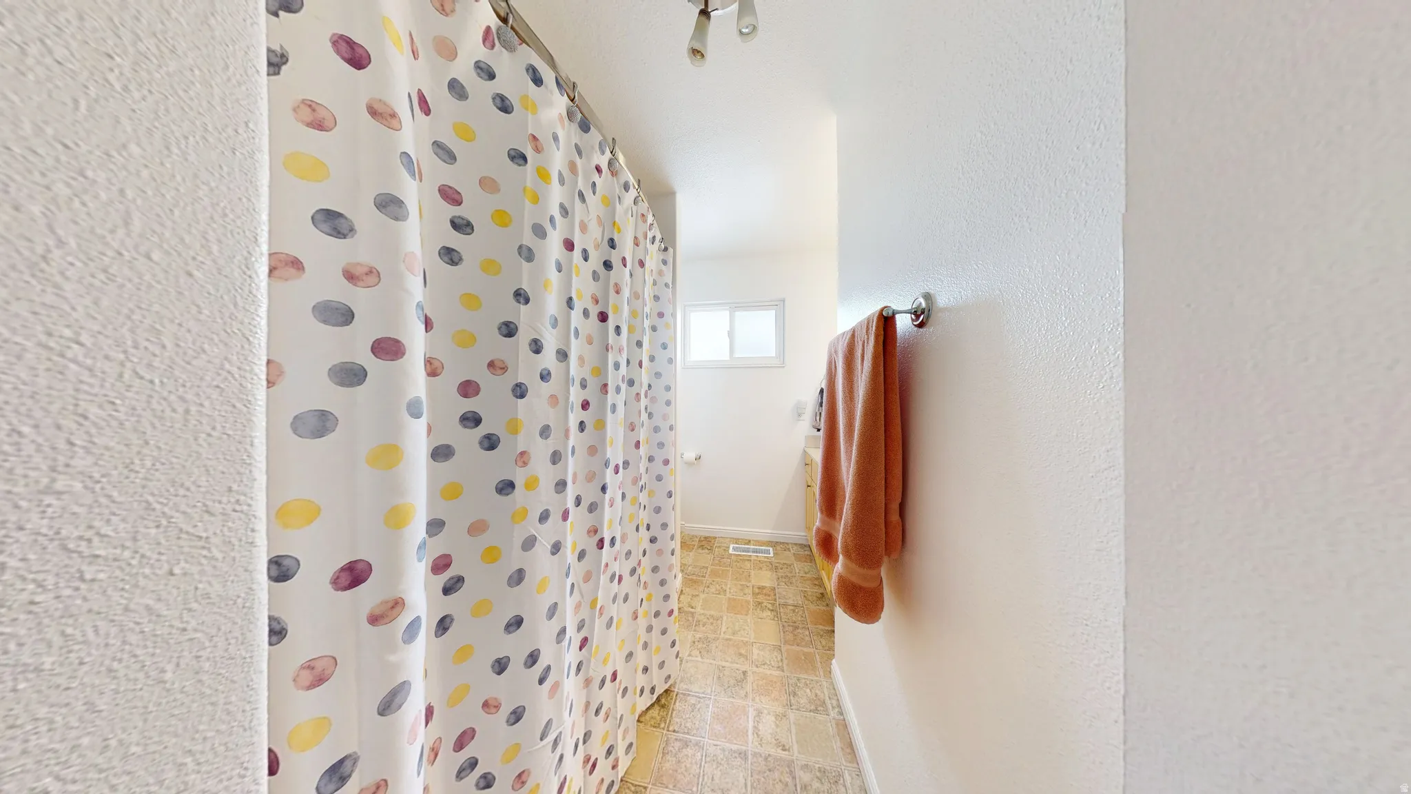 Full bath featuring stone finish floors, a shower with shower curtain, and a textured wall
