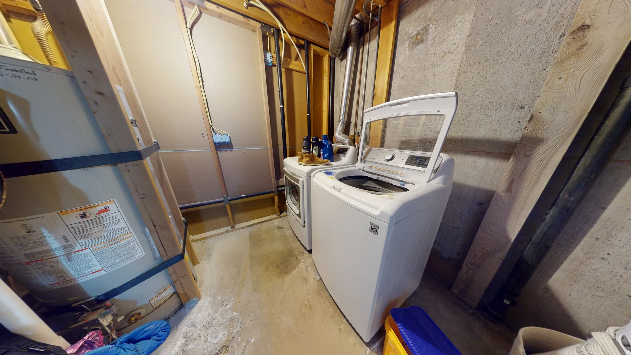 Laundry area featuring water heater, concrete flooring, and washing machine and dryer