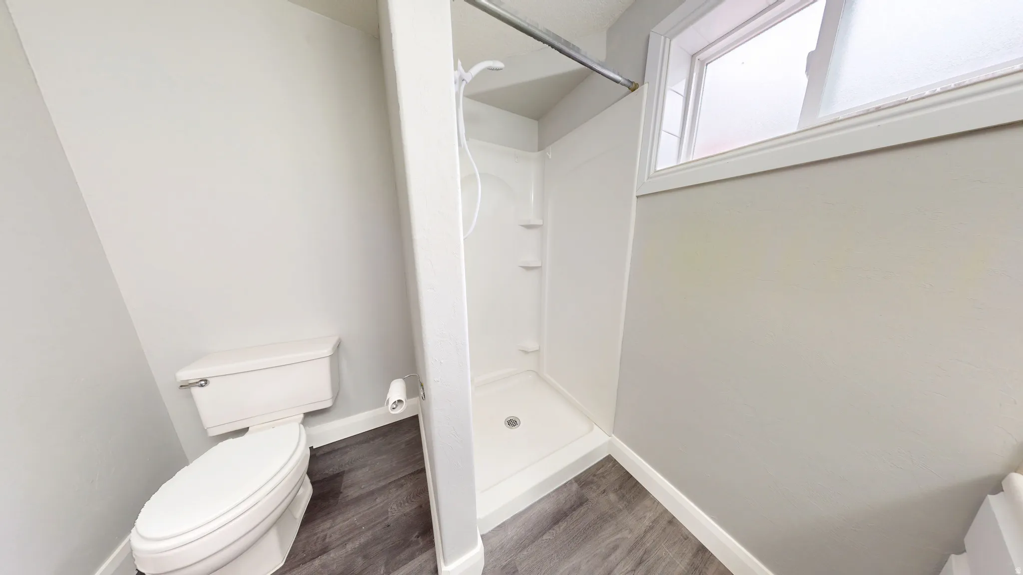 Bathroom with a stall shower and dark wood finished floors