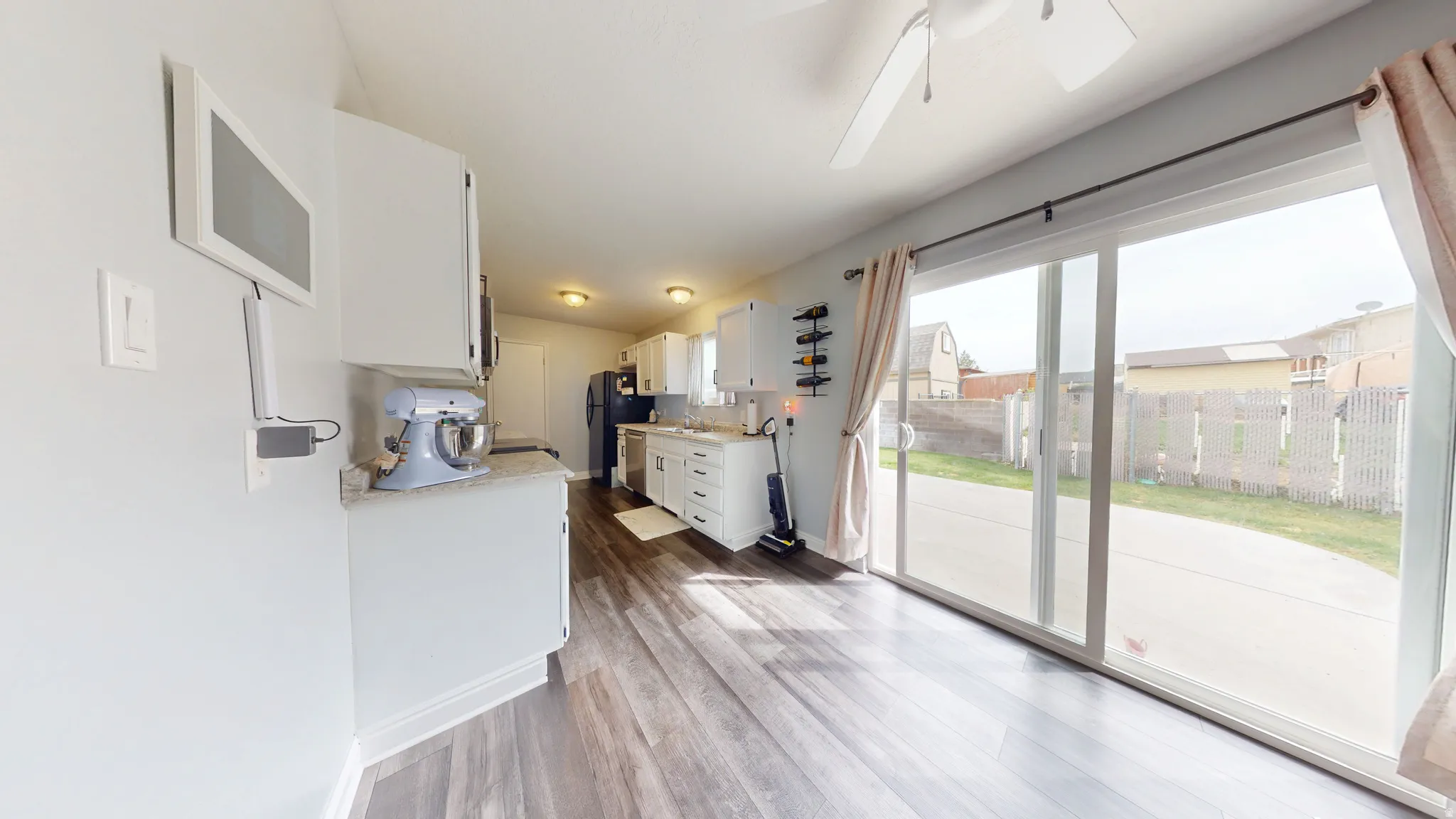 Kitchen with white cabinets, light wood finished floors, a ceiling fan, dishwasher, and light stone countertops