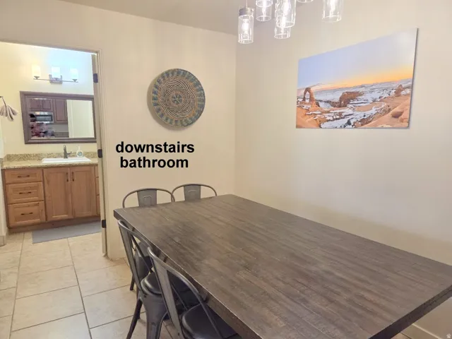 Downstairs bathroom off the dining room with light tile patterned floors and suspended lighting