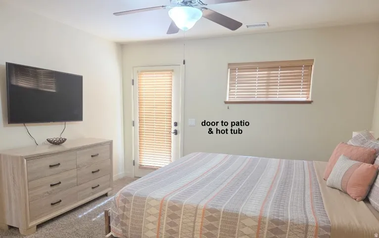 Master bedroom with light colored carpet and ceiling fan. opens up to Hot Tub.