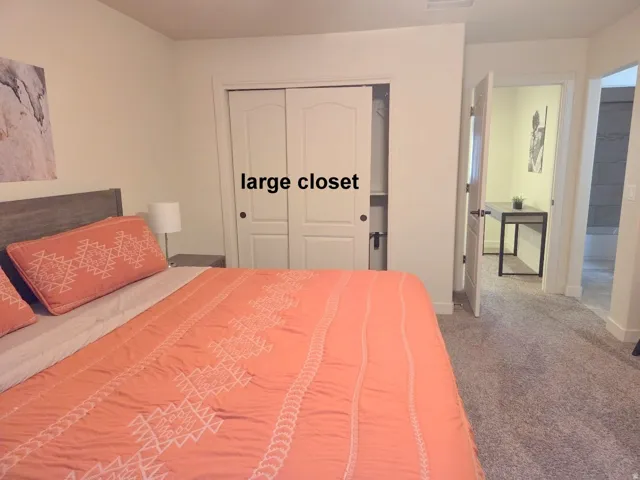 2nd Master bedroom with light carpet and a closet opens to ensuite bathroom.