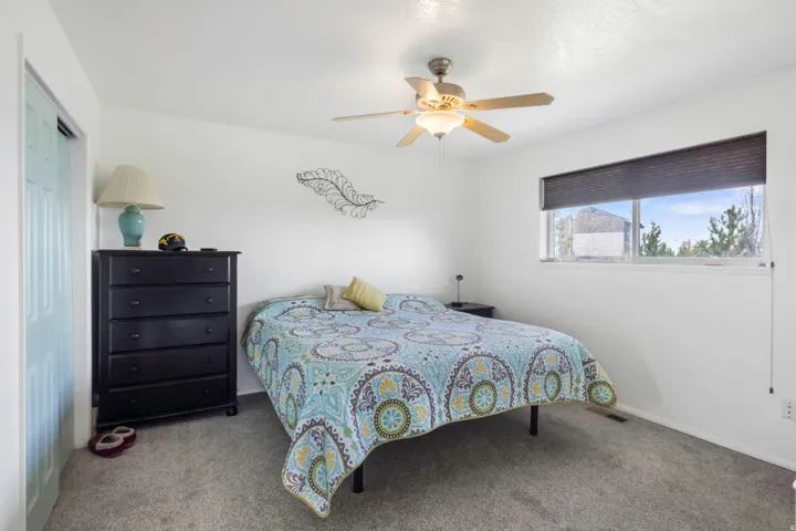 Carpeted bedroom with ceiling fan and a closet