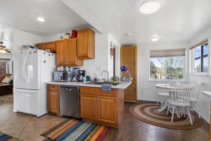 Kitchen featuring light countertops, healthy amount of natural light, stainless steel appliances, wood finish cabinetry, and a textured ceiling