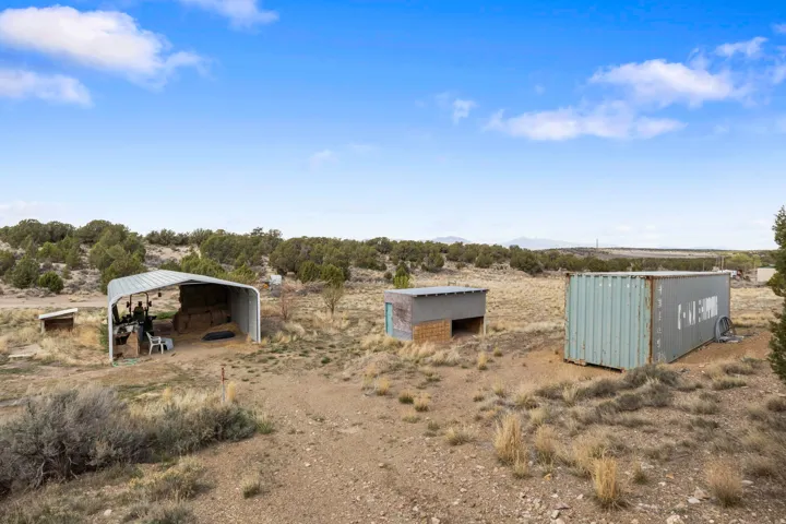View of yard with a rural view, a detached carport, and an outdoor structure