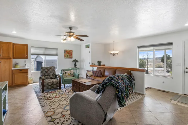 Living area with light tile patterned floors, a ceiling fan, a textured ceiling, and hanging lights