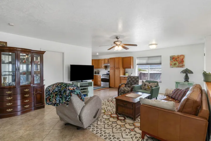 Living area with light tile patterned flooring, ceiling fan, and a textured ceiling