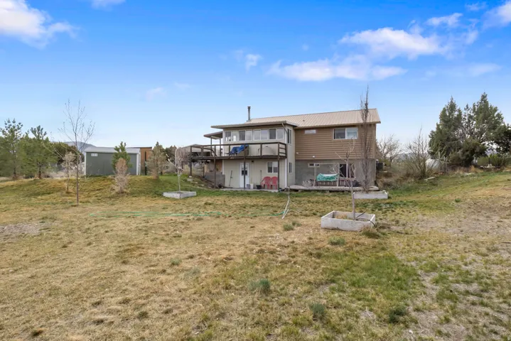 Back of house featuring a deck, a yard, and a metal roof