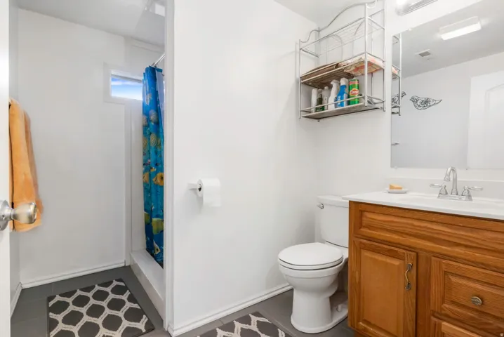 Bathroom featuring a stall shower, vanity, and dark tile patterned floors