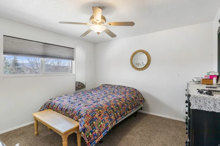 Bedroom with a ceiling fan and dark carpet