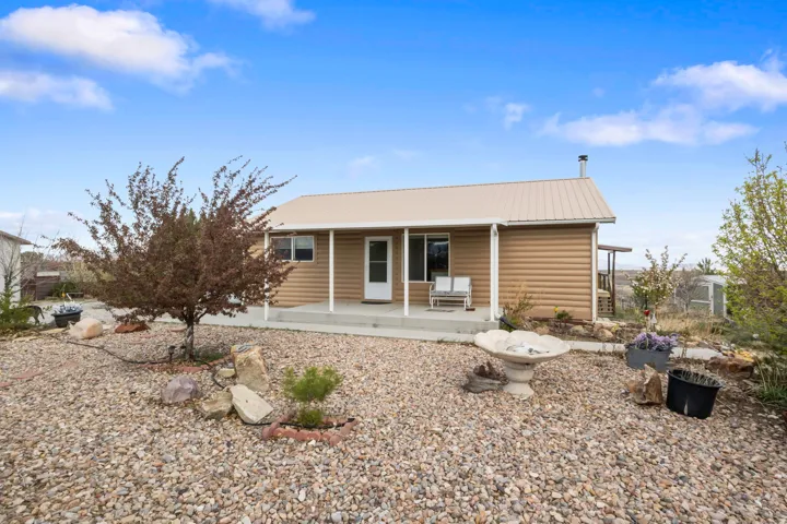 Rear view of property featuring a porch, a metal roof, and faux log siding