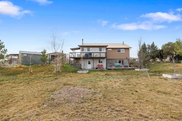 Rear view of property with a yard and a balcony