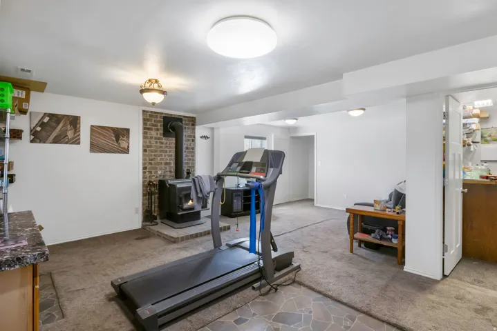 Exercise room featuring dark carpet and a wood stove