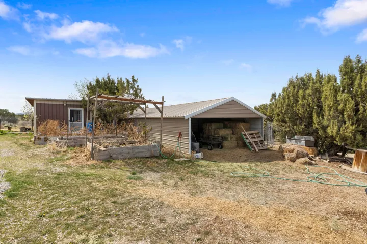 Rear view of property with an outdoor structure, a garden, an outbuilding, board and batten siding, and a wooden deck