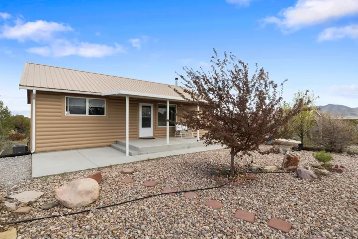 Back of house with a metal roof, faux log siding, a porch, and a mountain view