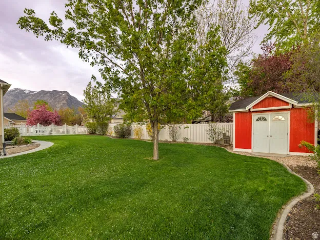 Fenced backyard featuring a shed and a mountain view
