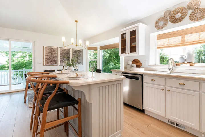 White kitchen featuring a substantial island with beadboard paneling, light-toned countertops, and wood-finish flooring