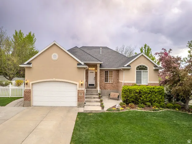 Single story home with brick siding, a garage, concrete driveway, and stucco siding