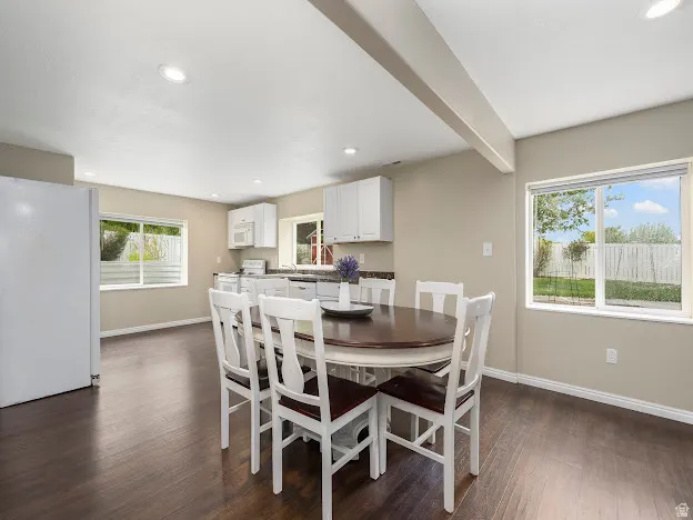 Dining room with dark wood-style floors, recessed lighting, and beam ceiling